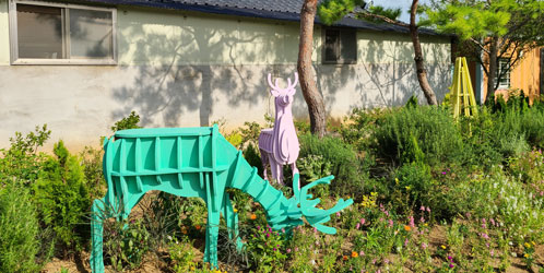 기왓장으로 된 집앞 잔디밭에 사슴 동상이 있다