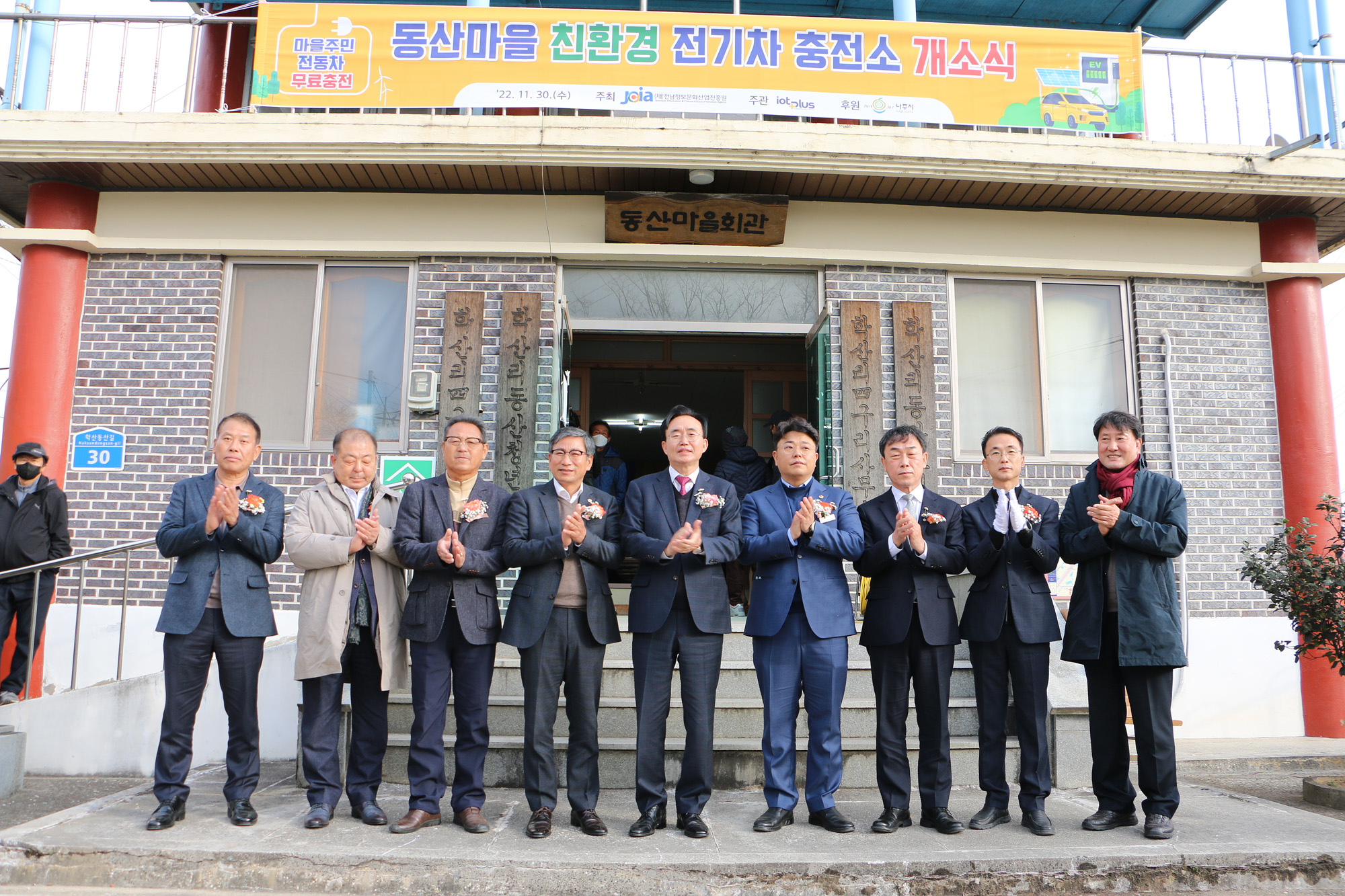 동산마을회관 입구에서 관계자들과 박수를 치며 기념촬영을 하는 모습