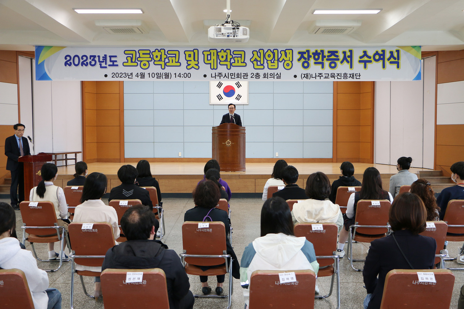 나주교육진흥재단 신입생 장학금 수여식(대학생, 고등학생) 학생들의 앉아 있는 뒷모습이 보이고 나주시장이 인사말을 하고 있는 모습