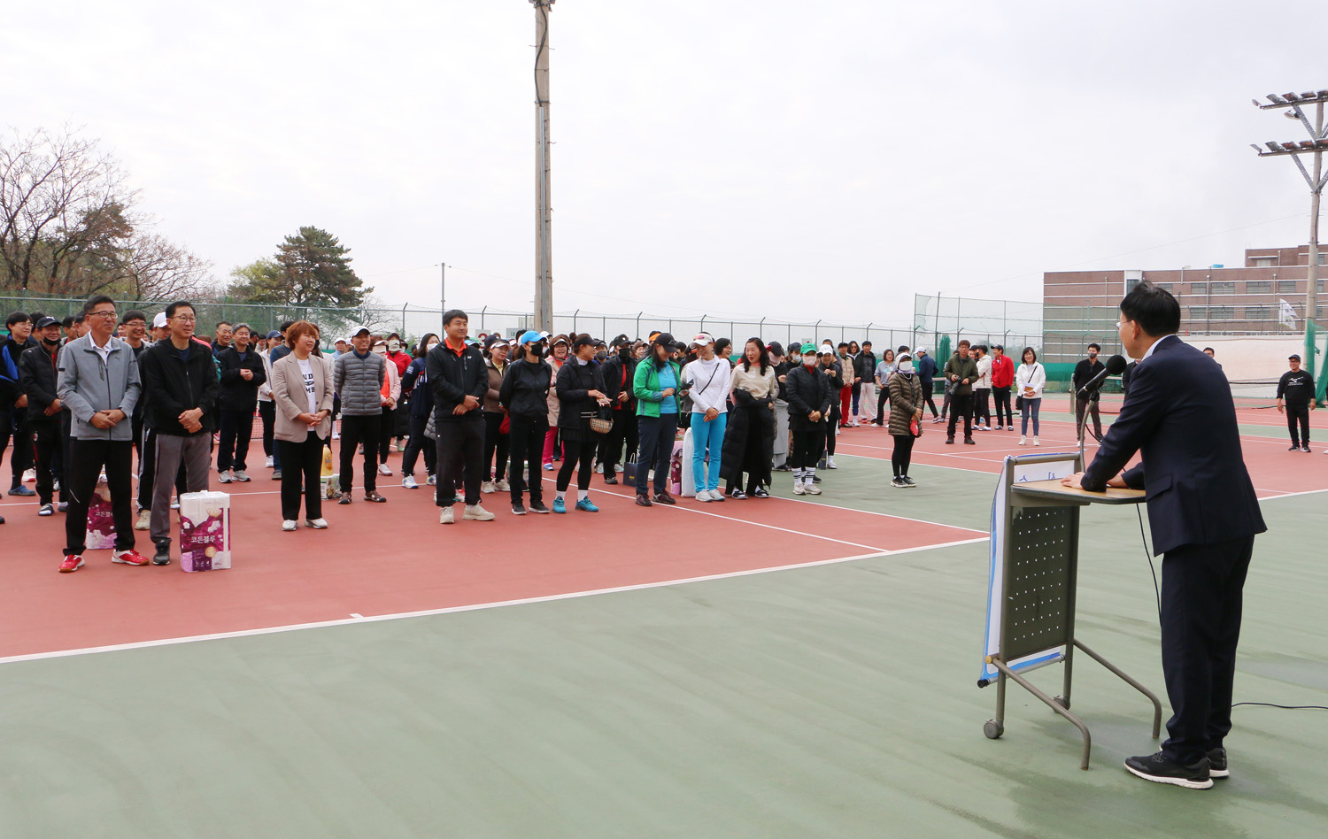 나주배꽃배 전남, 광주 테니스대회 개회식 대회에 참가한 시민들의 서있는 모습이 보이고 나주시장이 축사를 하는 옆 모습