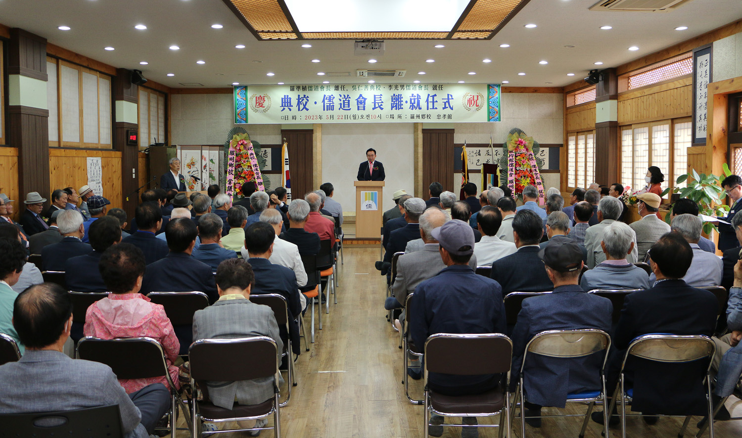 나주향교 전교, 성균관 유도회장 이.취임식 나주시장의 축사모습과 참석자들의 앉아있는 뒷모습이 보이는 전면