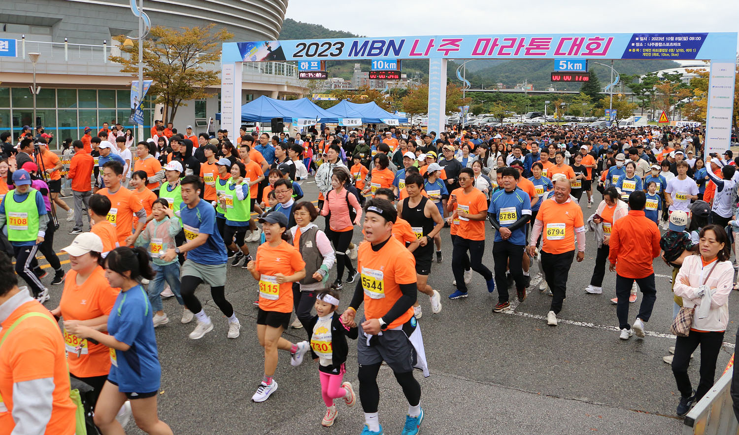 MBN 나주 마라톤 대회 5키로 참가자들이 스타트하고 있는 모습 주촹색 유니폼을 입은 선수들이 많음