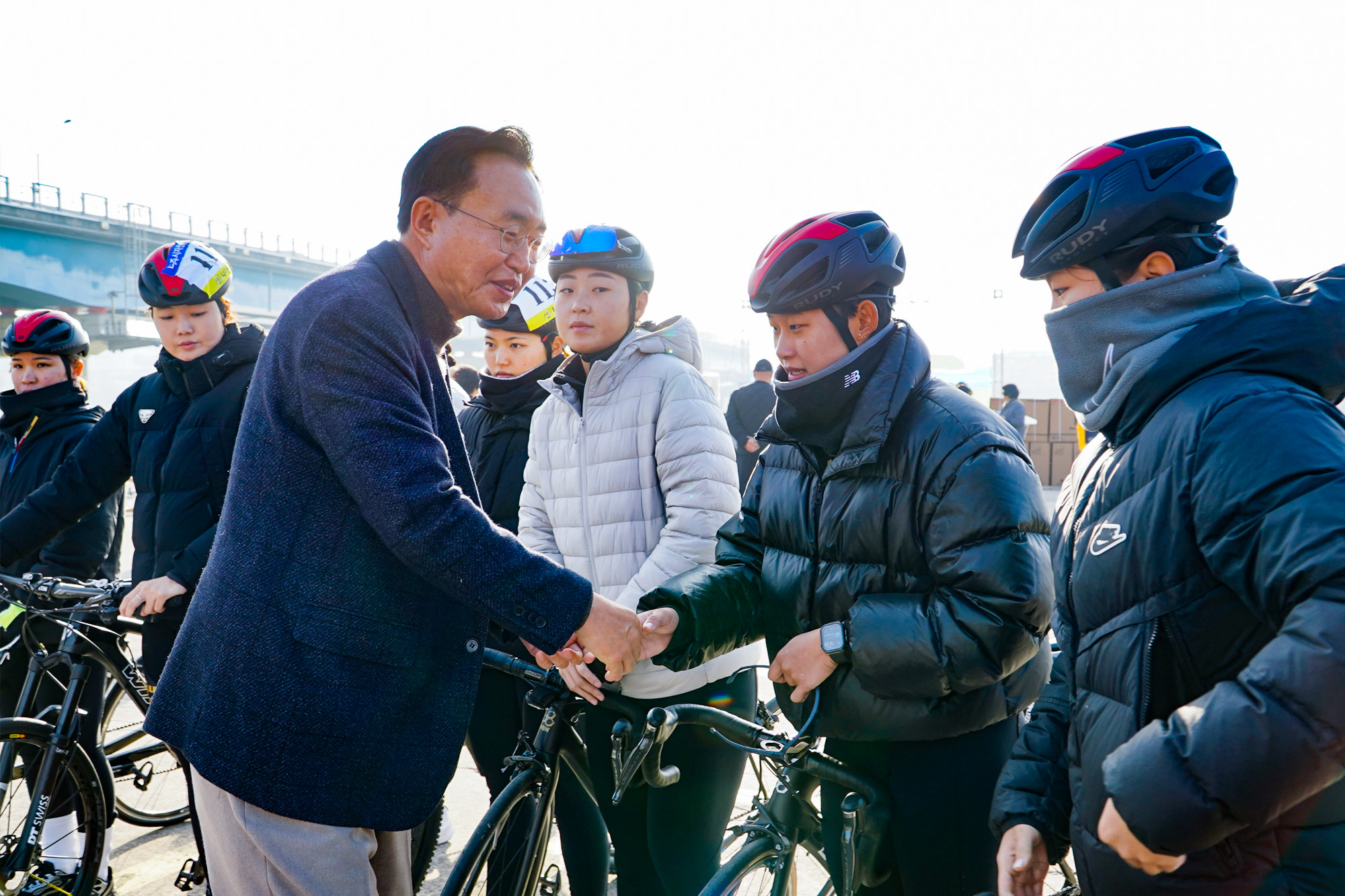 윤병태 나주시장이 자전거 헬멧과 운동복을 착용한 사이클리스트와 야외에서 악수를 나누며 미소 짓고 있다.