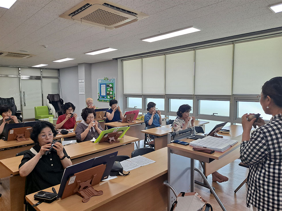 교육장에서 오카리나를 교육중인 강사와 배우는 교육생들 모습