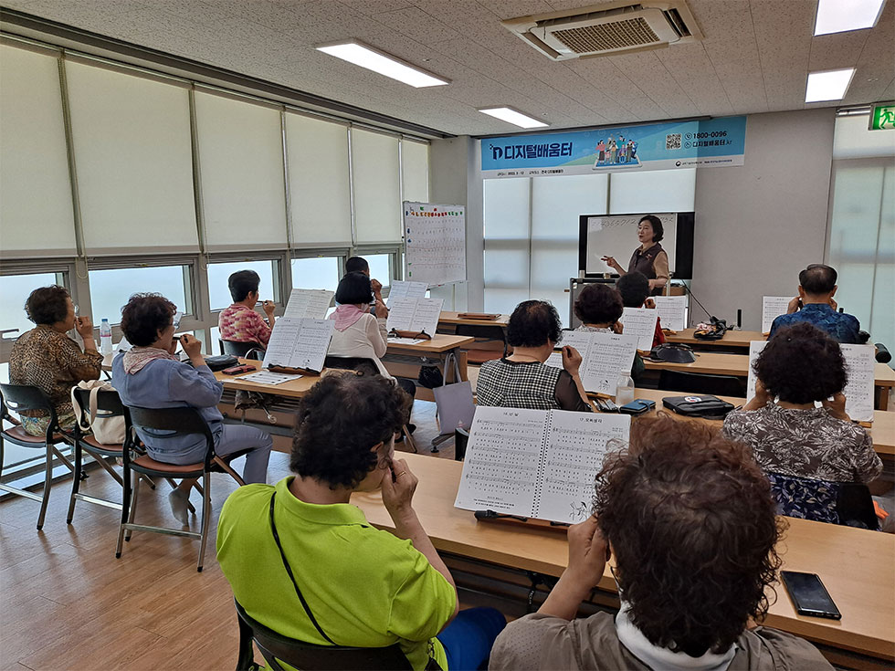 교육장에서 하모니카를 교육중인 강사와 배우는 교육생들 모습