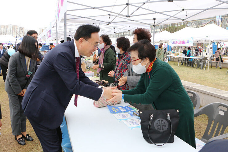 제1회 빛가람동민의 날 행사 행사부스의 여자어르신과 악수를 나누는 나주시장 모습