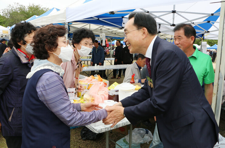 공산면민의 날 행사 나주시장이 행사장 부스에 있는 면민과 악수를 하고 있는 모습