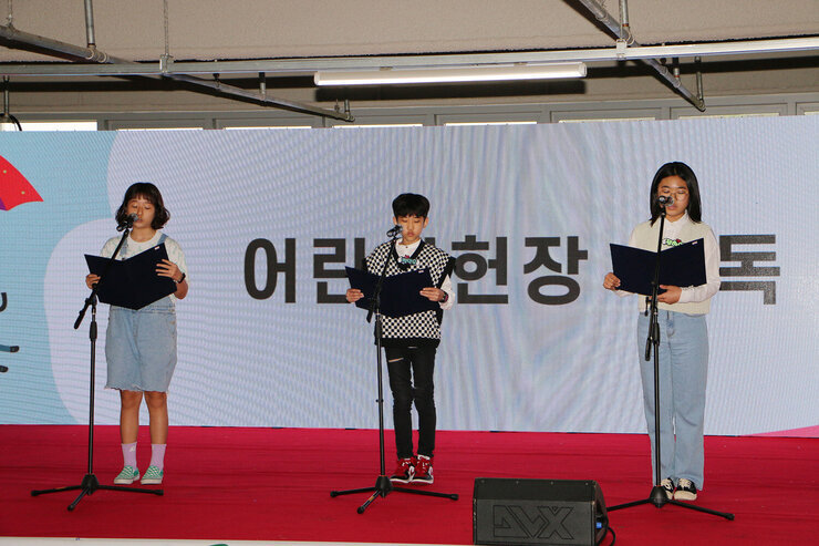 2023년 나주 어린이 큰잔치 무대위 중앙에 남자 어린이 한명, 양 옆으로 여자 어린이 두명이 어린이 헌장을 낭독하고 있는 모습