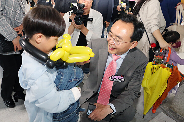 2023년 나주 어린이 큰잔치 나주시장이 풍선아트를 목에 건 남자아이에게 키를 맞춰 앉으며 인사를 나누는 모습