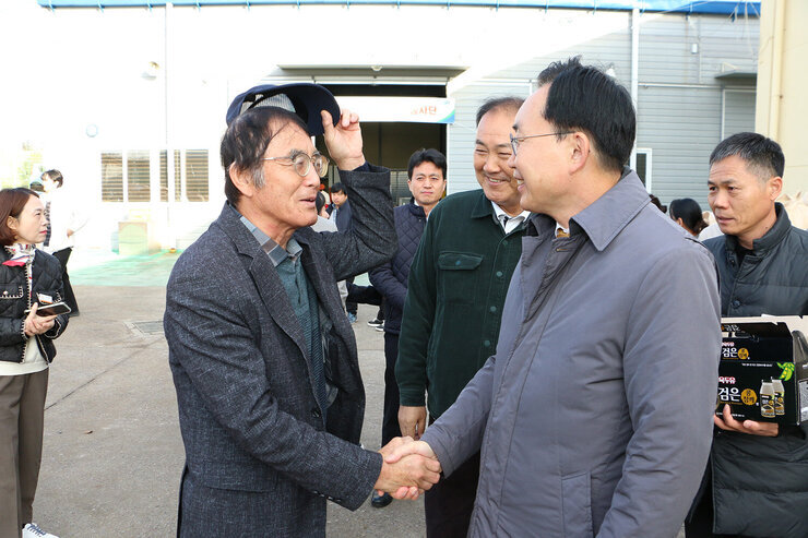 공공비축미곡 수매현장 방문 나주시장이 모자를 쓴 농민 어르신과 악수를 하며 인사를 나누는 모습