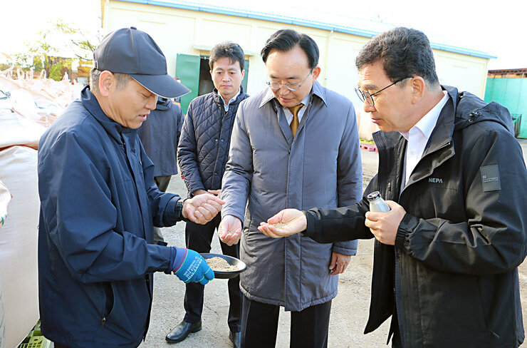 공공비축미곡 수매현장 방문 나주시장과 국회의원이 남성 검사관의 설명을 들으며 쌀을 살펴보고 있는 모습