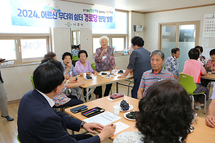 무더위 쉼터 현장 점검 경로당 최고령 여성 어르신이 자리에 서서 나주시장에게 건의사항을 말하고 있으며 어르신을 바라보며 듣고 있는 나주시장의 뒷모습