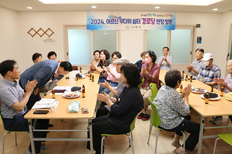 무더위 쉼터 현장 점검 나주시장이 입식테이블에 서서 허리굽혀 어르신들께 인사를 하고 있는 모습과 박수를 쳐 주고 있는 어르신들의 모습