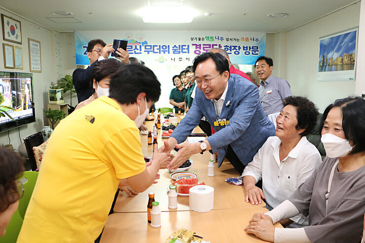 무더위 쉼터 현장 점검 나주시장이 경로당을 방문하여 여성 어르신과 두손으로 악수를 나누는 모습 나주시장이 활짝 웃고 있다