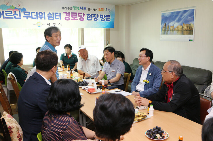 무더위 쉼터 현장 점검 남성 어르신이 입식테이블 자리에 서서 마무리 하는 인사말을 전달하고 있고 듣고 있는 나주시장과 어르신들의 모습