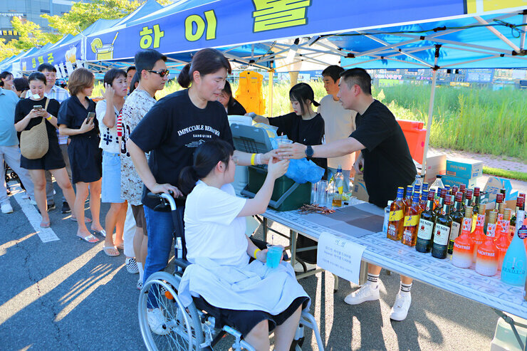 나주 빛가람 하이볼 페스티벌 행사장에 마련된 부스에서 하이볼을 제조하여 휠체어를 탄 시민에게 전달하고 있는 모습