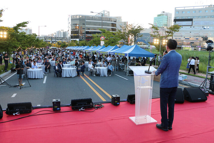 나주 빛가람 하이볼 페스티벌 무대 위에서 인사말을 하고 있는 나주시장 뒷편에서 촬영한 모습 참석한 시민들이 원형테이블에 앉아 있는 모습도 보인다 