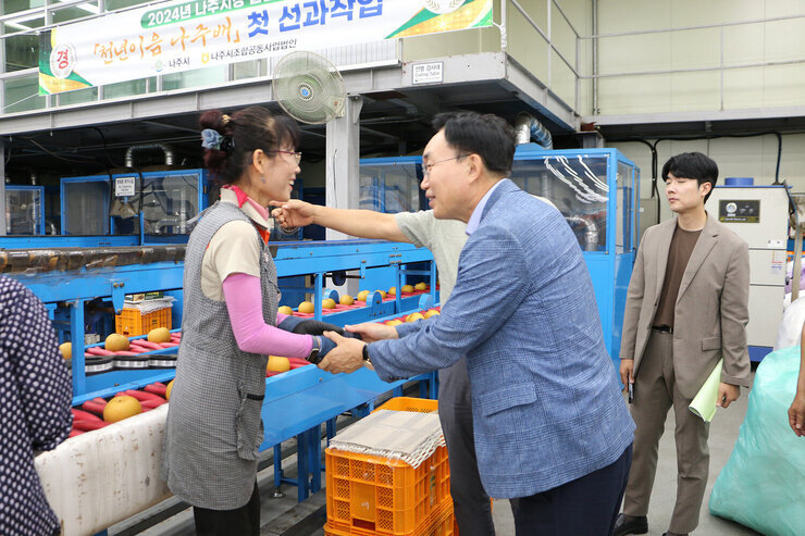 추석 명절 배 선과장 방문 나주시장이 선과장에서 배 분류 작업을 하고 있는 여성분과 두손을 맞잡으며 인사를 나누는 모습