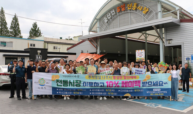 추석 명절맞이 공산5일시장 장보기 행사 나주시장과 공산면장 및 시청 직원 등이 플래카드를 펼치고 화이팅을 하며 기념촬영을 하고 있는 모습