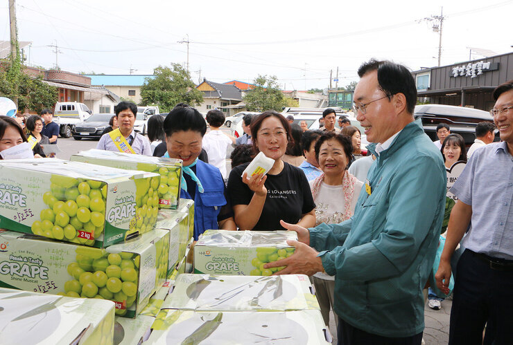 추석 명절맞이 공산5일시장 장보기 행사 나주시장이 샤인머스켓을 판매하는 여성 상인과 샤인머스켓 상자를 보며  웃고 잇는 모습
