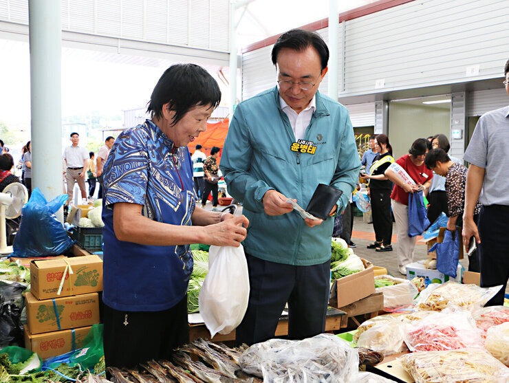 추석 명절맞이 공산5일시장 장보기 행사 나주시장이 건어물을 판매하는 여성 상인에게 구매한 물품에 대해 나주사랑상품권을 들고 있는 모습