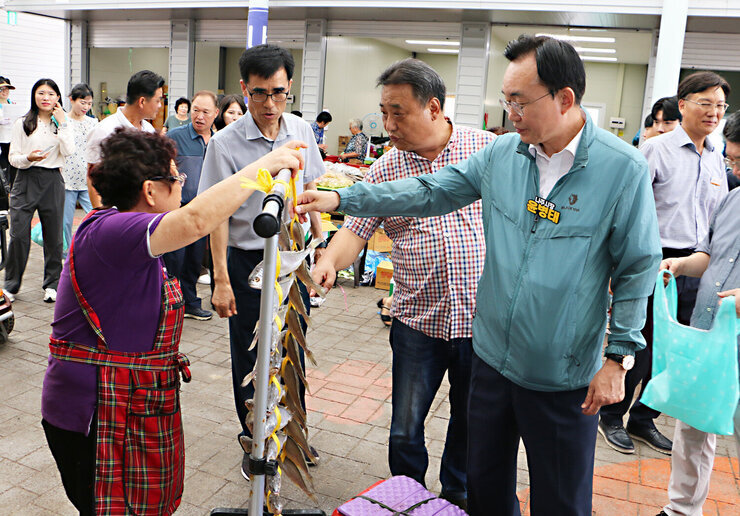 추석 명절맞이 공산5일시장 장보기 행사 나주시장이 어물전의 조기를 바라보며 꼬아진 조기를 한손으로 잡으며 살펴 보고 있는 모습