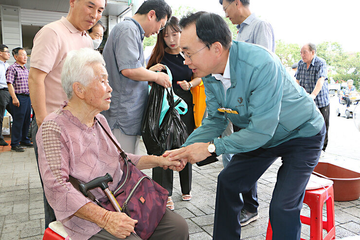 추석 명절맞이 공산5일시장 장보기 행사 나주시장이 장을 보러오신 여성 어르신의 손을 두손으로 잡으며 인사를 하고 있는 모습