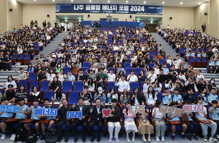 나주 글로벌에너지포럼 2024 시민특강 강연장 안 나주시장과 강사 및 참석자들이 자리에 앉아서 피켓을 들고 퍼포먼스를 하고 있는 모습