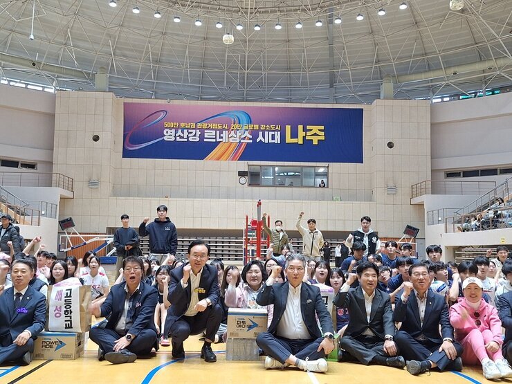 나주시배구협회장배 고등학교 남녀 배구대회 나주시장과 배구협회장 및 내빈들이  배구 코트 바닥에 앉아서 한손을 올리고 화이팅을 외치며 기념촬영을 하고 있는 모습