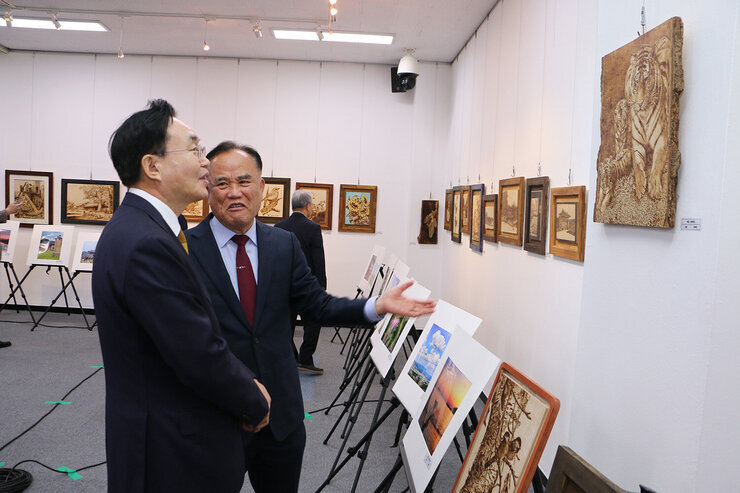 나준문화원의 날 기념식 행사장에 전시된 작품에 대해 나주문화원장이 설명을 하고 있고 나주시장이 듣르며 작품을 바라보고 있는 모습