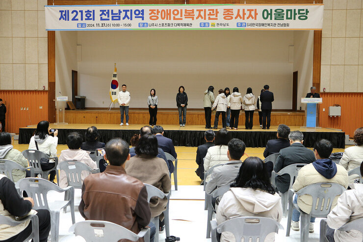 전남지역 장애인복지관 종사자 어울마당 행사 관계자가 무대 위에서 시상을 하고 있는 모습과 참석자들의 앉아 있는 뒷모습