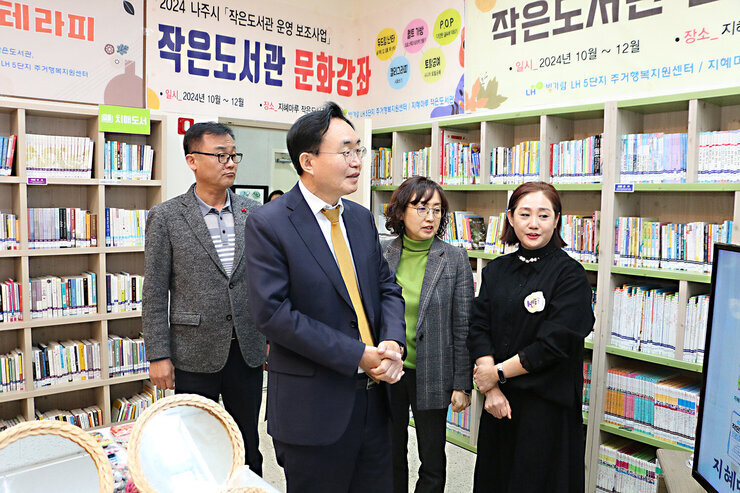 LH5단지 프로그램 성과나눔 전시회 나주시장이 LH5단지 도서관의 프로그램에 대해 관계자의 설명을 듣고 있는 모습