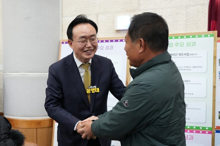 윤병태 나주시장이 한 남성 참석자와 악수를 나누며 환하게 웃고 있는 클로즈업 사진