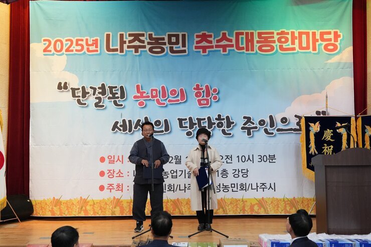 '2025년 나주농민 추수대동한마당' 무대 위에서 중년 남녀 두 명이 마이크 앞에서 순서를 진행하고 있는 모습