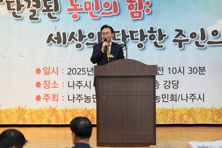 윤병태 나주시장이 단상에 서서 마이크를 잡고 연설하고 있는 모습. 배경에는 '단결된 농민의 힘: 세상의 당당한 주인으로'가 적힌 현수막과 행사 일시가 보인다.