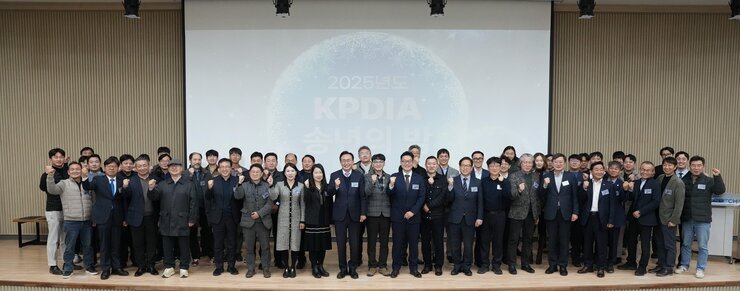  많은 인원이 행사장에서 단체 사진을 촬영하며 주먹을 쥐고 있는 모습. 배경 스크린에 '2025년도 KPDIA 송년의 밤'이라고 적혀 있음