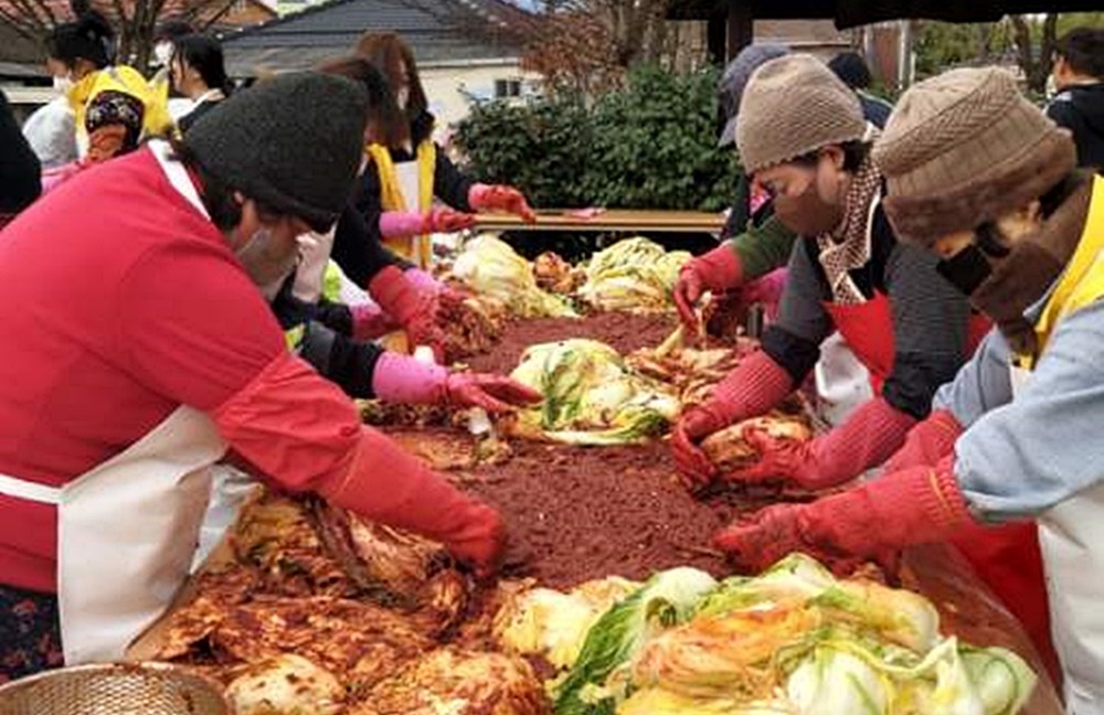 사랑의 김장 나눔에 참석한 봉사자들이 나란히 서서 배추에 양념을 버무리고 있는 모습