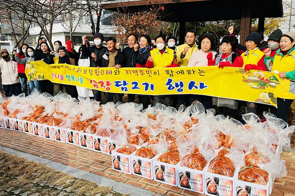 사랑의 김장 나눔행사에 참석한 관계자들과 봉사자들이 김치가 담긴 박스를 앞에두고 단체로 기념촬영을 하는 모습