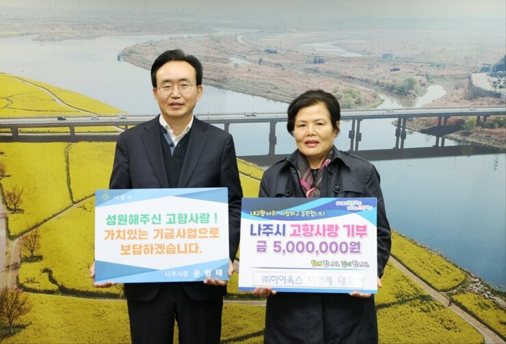왼쪽에 시장님이 성원해주신  고향사랑! 가치있는 기금사업으로 보답하겠습니다. 라고 적힌 팻말을 들고 오른쪽에 나주시 고향사랑 기부 금 5,000,000원 (주)하이옥스 이영례 대표라고 적힌 팻말을 들고 기념 촬영 중이다