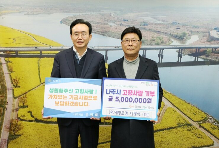 왼쪽에 시장님이 성원해주신  고향사랑! 가치있는 기금사업으로 보답하겠습니다. 라고 적힌 팻말을 들고 오른쪽에 나주시 고향사랑 기부 금 5,000,000원 (유)예향조경 나영식 대표라고 적힌 팻말을 들고 기념 촬영 중이다