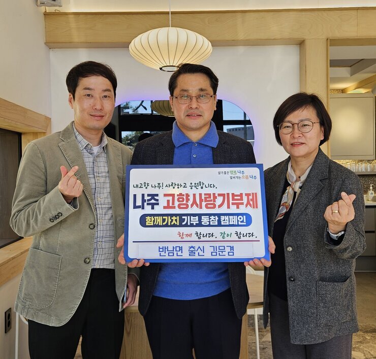 살기좋은 행복 나주 앞서가는 으뜸 나주 내고향 나주! 사랑하고 응원합니다. 나주시 고향사랑 기부 금 5,000,000원 함께 합니다. 같이 합니다. 반남면 출신 김문겸 이라고 적힌 팻말을 들고 있는 김문겸과 베이지 색 자켓을 입고 있는 남성, 회색 자켓을 입고있는 여성이 손하트를 하고 있다