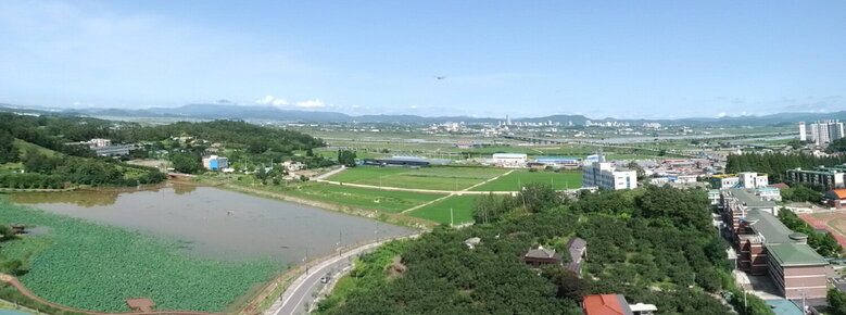 위에서 찍은 사진( 왼쪽에는 논들이 보이고 오른쪽에는 건물들이 보인다)