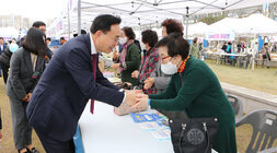 제1회 빛가람동민의 날 행사 행사부스의 여자어르신과 악수를 나누는 나주시장 모습