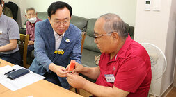 무더위 쉼터 현장 점검 나주시장이 입식테이블 바로 옆 남성 어르신께 수박 한조각을 두손으로 드리고 있는 모습