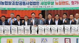 나주쌀 새청무 헝가리 첫 수출 상차식 근접촬영한 조합법인 앞 마당에서 나주시장과 나주시의회의장, 각 단위농협 조합장 및 관계자들이 행사를 위해 새청무 쌀이 놓여진  긴 테이블 뒤에 서서 화이팅을 하며 기념촬영을 하고 있는 모습