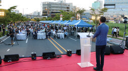 나주 빛가람 하이볼 페스티벌 무대 위에서 인사말을 하고 있는 나주시장 뒷편에서 촬영한 모습 참석한 시민들이 원형테이블에 앉아 있는 모습도 보인다 