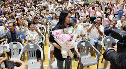 파리올림픽 금메달리스트 안세영 선수 나주 환영행사 안세영 선수가 행사장으로 입장하여 꽃다발을 들고 앞세 서 있고 참석한 시민 등이 앉아서 박수와 환호를 해주고 있는 모습