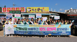 추석 명절맞이 영산포 풍물시장 장보기 행사 나주시장과 시청 담당 부서 직원 등이 전통시장 이용 페이백의 내용의 현수막을 펼치고 화이팅을 하며 기념촬영을 하고 있는 모습