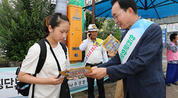 민, 관, 경 합동 어린이 교통안전 캠페인 나주시장이 횡단보도 앞에 서 있는 여자 어린이에게 홍보 전단지를 전달하며 설명을 하고 있는 모습