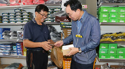 추석 명절맞이 세지5일장 장보기 행사 나주시장이 신발가게의 남성 상인분에게 고무신을 구입하고 나주사랑상품권을 건네고 있는 모습